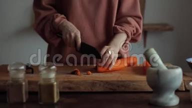 一位年轻女子用<strong>一把</strong>大刀切胡萝卜，在厨房里做饭